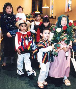 photo of children bringing flowers and flags to lay at the feet of Our Lady of Guadalupe statue