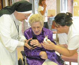 photo of Mother Marie Julie Saegaert, resident Selma Hicks (center), and Certified Nursing Assistant Marija Ramic cuddling two bunnies at St. Elizabeth Nursing Home