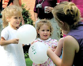 photo of Trea and Felicity Klingele chatting with Mary Grace Lyons, held by her mother, Athena Lyons, at the Diocesan Family Picnic on July 23