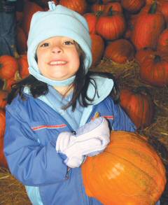 photo of Jenna Wagner, a kindergarten student at St. Peter School in Ashton, holding up the pumpkin she chose during a school field trip to nearby Kalscheuer's pumpkin farm