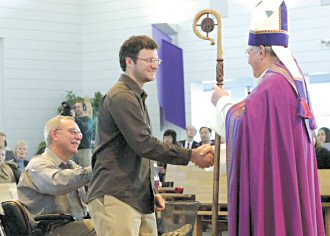 photo of Kyle Dziubla, a candidate with St. Andrew Parish, Verona, presented by his sponsor Les Werner, shaking hands with Bishop Robert C. Morlino